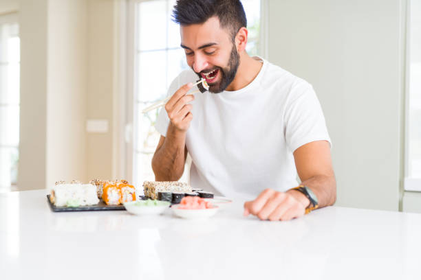 istock Handsome man smiling happy enjoying eating fresh colorful asian sushi using chopsticks 1167774938