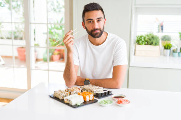istock Handsome hispanic man eating asian sushi using chopsticks with a confident expression on smart face thinking serious 1167774939