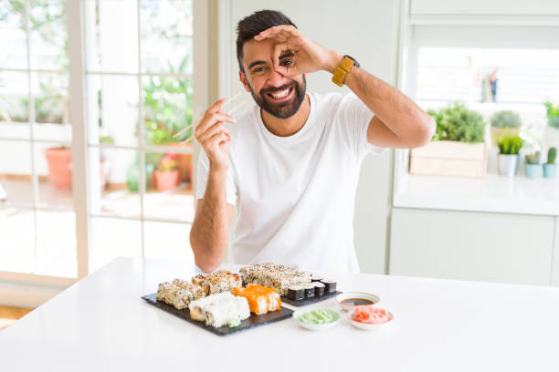 istock Handsome hispanic man eating asian sushi using chopsticks with happy face smiling doing ok sign with hand on eye looking through fingers 1167774942