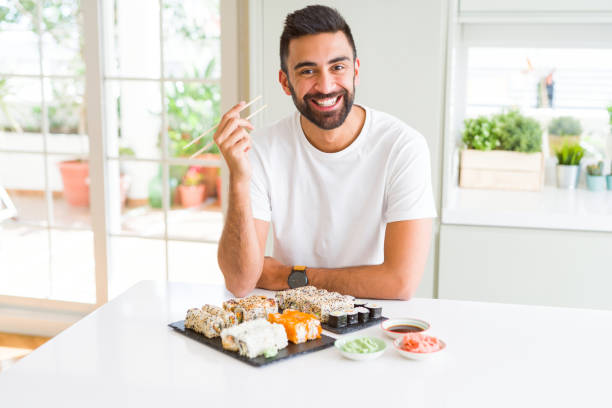 istock Handsome hispanic man eating asian sushi using chopsticks with a happy face standing and smiling with a confident smile showing teeth 1167774945