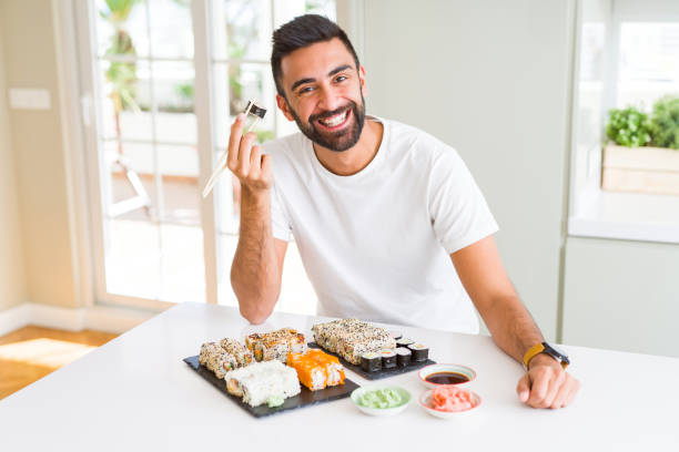 istock Handsome man smiling happy enjoying eating fresh colorful asian sushi using chopsticks 1167774946