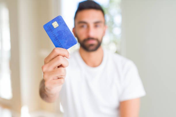 istock Handsome hispanic man holding credit card with a confident expression on smart face thinking serious 1167775433