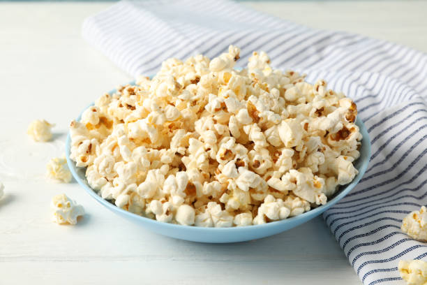 istock Towel and plate with popcorn on white wood background, copy space 1167775697