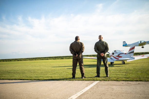 istock Rear view of two pilots standing near airplane runway 1167777585