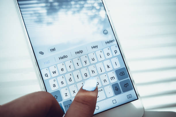 Female hand with blue nails is typing on a white phone a message