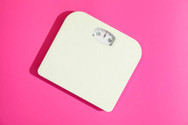 White weigh scales on pink background, space for text