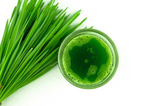 top view of wheat grass juice in glass on white background