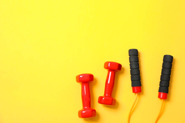 istock Dumbbells and jump rope on yellow background, space for text 1167780935