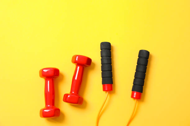 istock Dumbbells and jump rope on yellow background, space for text 1167780995