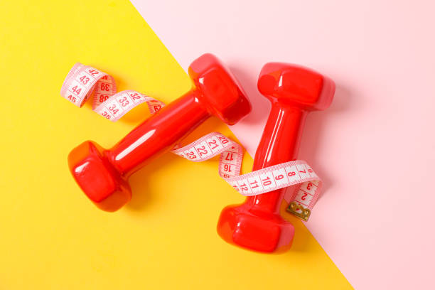 istock Dumbbells and measuring tape on two tone background, copy space 1167781005