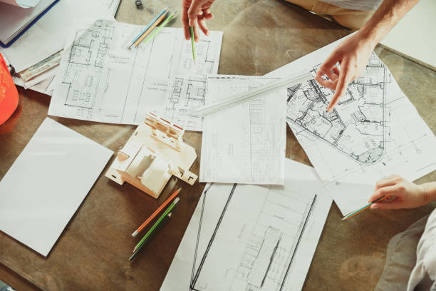 istock Foreman or achitect shows house, office or store design plans to a young couple 1167781084