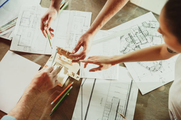 istock Foreman or achitect shows house, office or store design plans to a young couple 1167781087