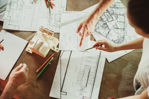istock Foreman or achitect shows house, office or store design plans to a young couple 1167781088