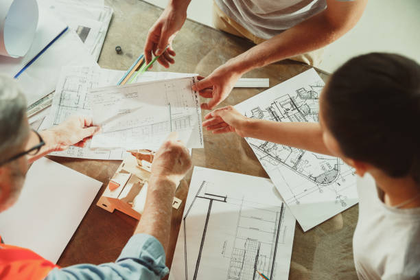 istock Foreman or achitect shows house, office or store design plans to a young couple 1167781111
