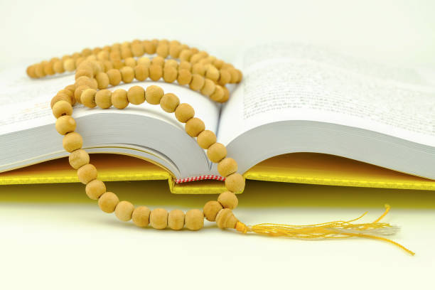 rosary on yellow praying book rosary on yellow praying book on white background chanting stock pictures, royalty-free photos & images