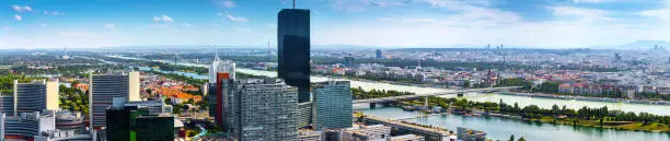 Stunning aerial panoramic cityscape view austrian capital city of Vienna. Modern glass-concrete skyscrapers in Donau City. Prater park on the Danube - of the largest river in Europe. Hot summer day.