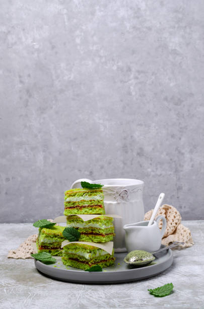 Traditional green sponge cake with cream and jam on slate background. Selective focus.