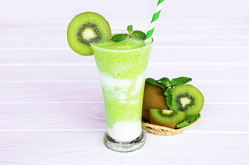 Kiwi yogurt fruit juice smoothie and green kiwi juice drink healthy  delicious taste in a glass for weight loss on a white wooden background.
