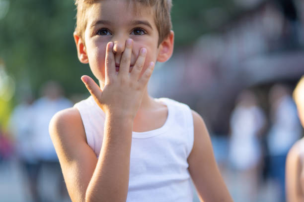 This cute blond 8 year old has clearly seen and smelled something nasty as he looks down squinting and holding his nose. 