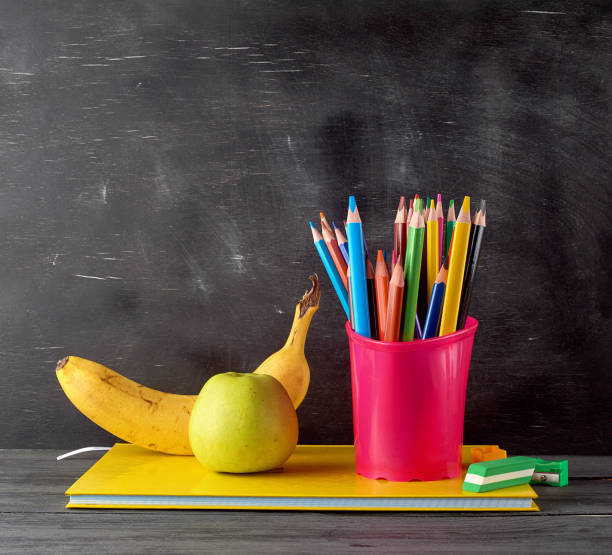istock ripe green apple, banana on a stack of notebooks 1167793409