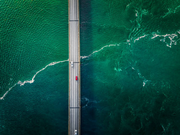 cars driving on a bridge with greenish flow of water under the bridge. - vista aérea de carro isolado imagens e fotografias de stock