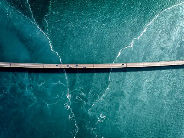 Aaerial photograph of the beautiful sea and bridge in Iceland. Cars are crossing the bridge to reach their destination.