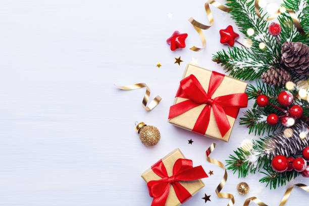 istock Beautiful Christmas composition on white background with golden Christmas gift boxes, snowy fir branches, conifer cones, holiday decoration and red berry. Top view. 1167799086