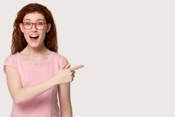 istock Amazed redhead woman point finger at copy space studio shot 1167799906