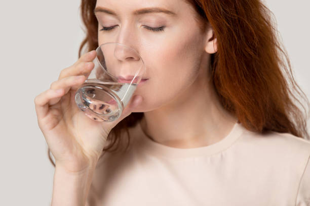 istock Close up young thirsty red-headed woman drinking clean water 1167799923