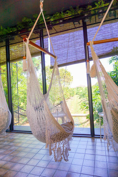 Empty white knitting rope swings hanging by the window in cafe, white hammock.