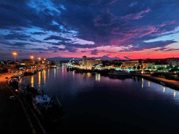 beleuchtete stadt am fluss gegen himmel bei sonnenuntergang - pescara stock-fotos und bilder