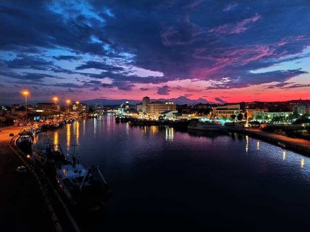città illuminata dal fiume contro il cielo al tramonto - pescara foto e immagini stock