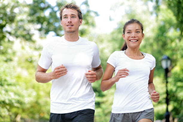 happy couple runners training in summer city park - asian ethnicity jogging female women imagens e fotografias de stock