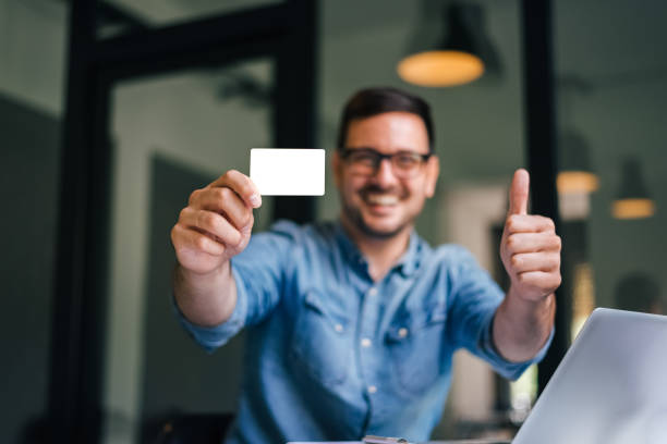 prendi in giro il percorso di ritaglio sfondo sfondo dimensione bianca dell'uomo sorridente della carta di credito standard che tiene la carta di credito vuota che mostra il pollice in su per la qualità del servizio e la soddisfazione del cliente - showing buying paying clipping path foto e immagini stock