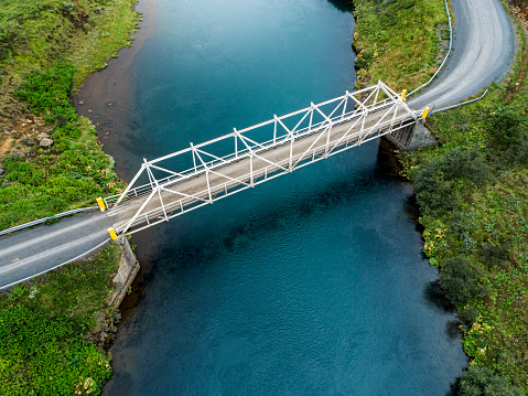 Aerial view of a bridge over a river in the countryside in Iceland viewing the colourful nature of Iceland