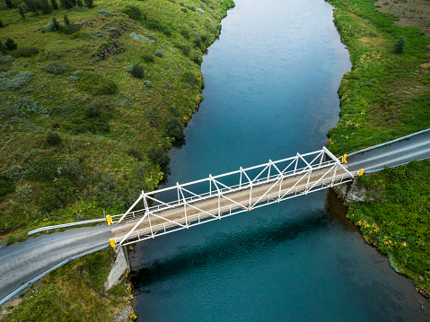 Aerial shot of a bridge over a river in beautiful nature in the colourful countryside of Iceland