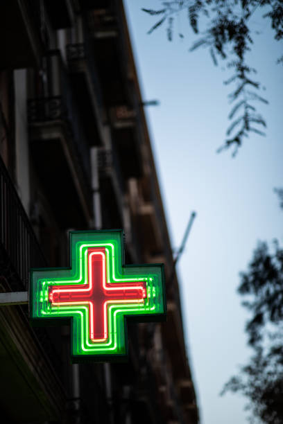 Pharmacy sign illuminated at night on spanish architecture facade with copy space Pharmacy sign illuminated at night on spanish architecture facade with copy space pomegranate in spanish stock pictures, royalty-free photos & images