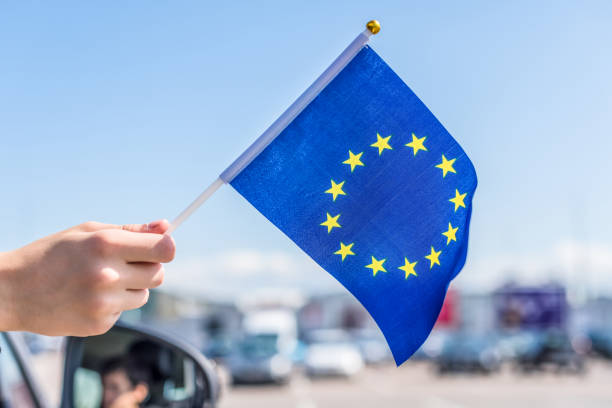 Boy holding Europe or European(EU) Flag from the open car window on the parking of the shopping mall. Concept Boy holding Europe or European(EU) Flag from the open car window on the parking of the shopping mall. Concept schengen agreement stock pictures, royalty-free photos & images