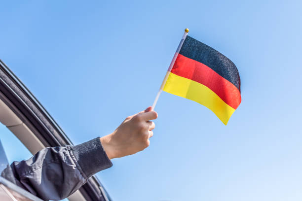 istock Boy holding Germany Flag from the open car window on the sky background. Concept. 1167806197