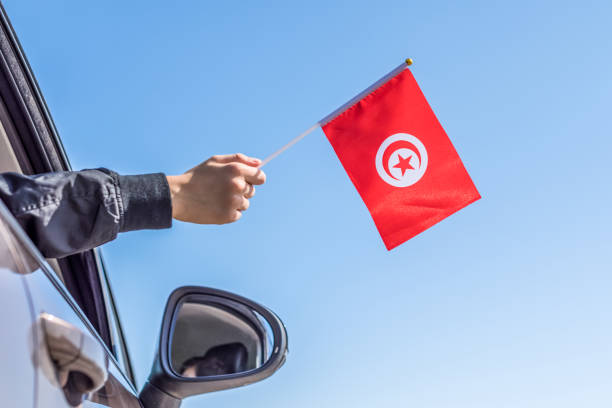 niño sosteniendo la bandera de túnez desde la ventana abierta del coche en el fondo del cielo. concepto. - women open traditional culture human hand fotografías e imágenes de stock