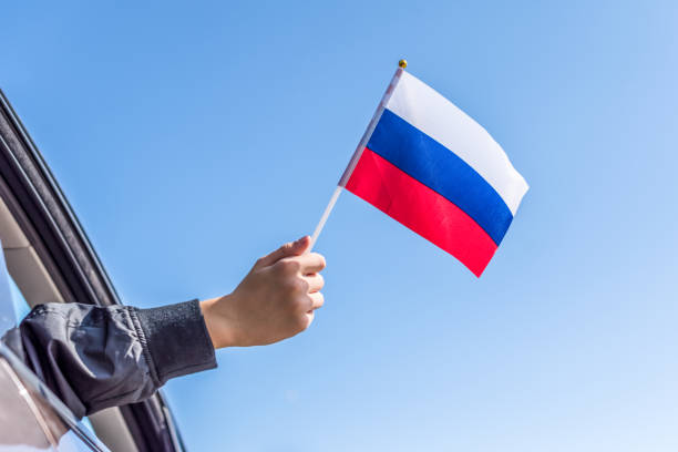 istock Boy holding Russian Flag from the open car window on the sky background. Concept 1167806272