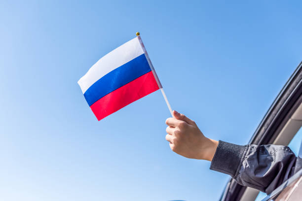 istock Boy holding Russian Flag from the open car window on the sky background. Concept 1167806343