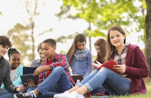 multiethnische gruppe von teenagern im park mit freunden. - mittelschule bücher stock-fotos und bilder