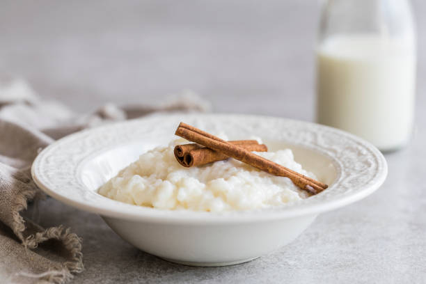 budino di riso con cannella e una bottiglia di latte - rice pudding foto e immagini stock