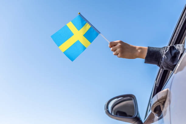 niño sosteniendo la bandera sueca desde la ventana abierta del coche en el fondo del cielo. concepto - women open traditional culture human hand fotografías e imágenes de stock