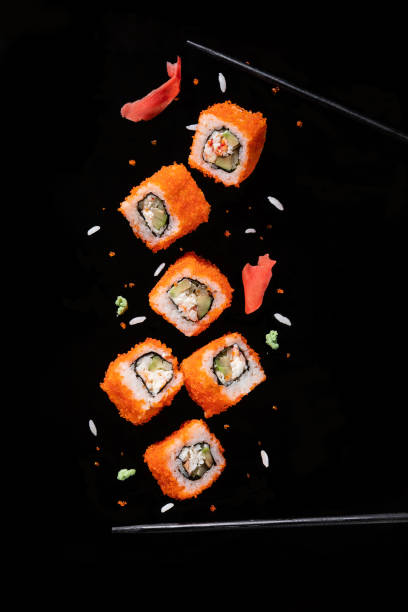 Sushi pieces between chopsticks, flying separated on black background. Sushi pieces between chopsticks, flying separated on black background. sushi photos stock pictures, royalty-free photos & images