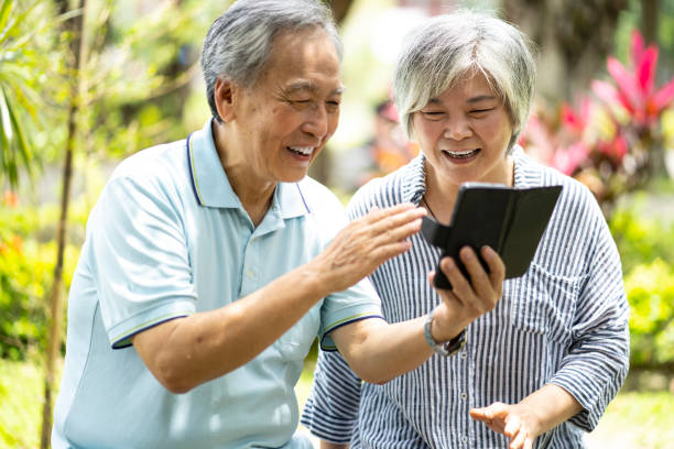 istock Smiling senior couple using phone in park 1167812336