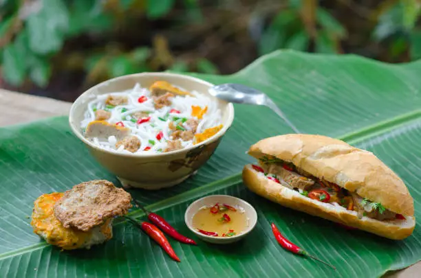 Photo of Banh Canh - Rice noodles soup with fried fish ball and Banh Mi Cha Ca - Vietnamese bread with fried fish and chili fish sauce inside. This is a typical combo for breakfast in south central of Vietnam