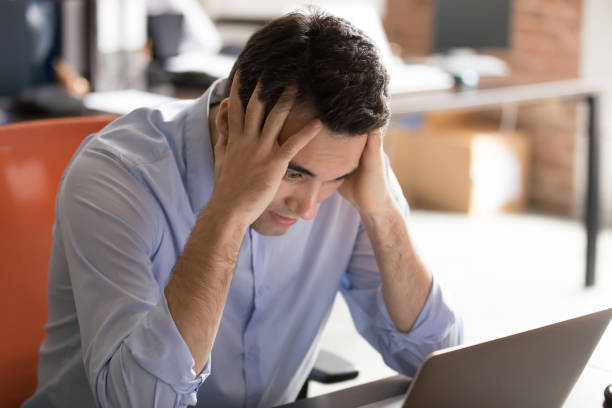 istock Businessman sitting at desk near computer having problems feels stressed 1167824866
