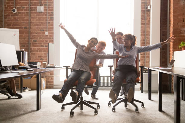 istock Diverse employees having fun laughing riding on office chairs 1167824895
